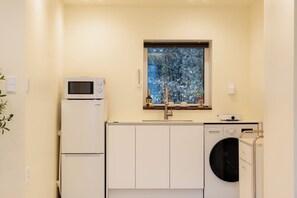 Een kleine keuken met een magnetron, een spoelbak en een wasmachine.