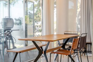 A dining area with a wooden table and chairs, large windows, and a view of the outdoors. - Boryeong Lavar Pool Villa (Boryeong)