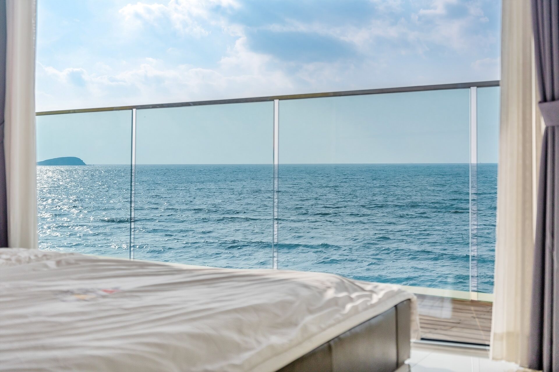 Ein Zimmer mit einem Bett und Meerblick durch ein Fenster.