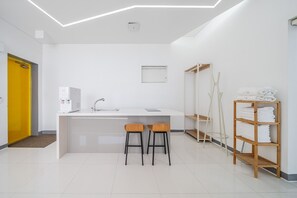 A modern bathroom with a white sink, two stools, a towel rack, and a shower area. - Boryeong Lavar Pool Villa (Boryeong)