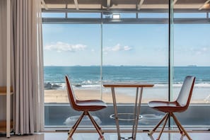 A room with a large window overlooking a beach, two chairs, and a small table. - Boryeong Lavar Pool Villa (Boryeong)