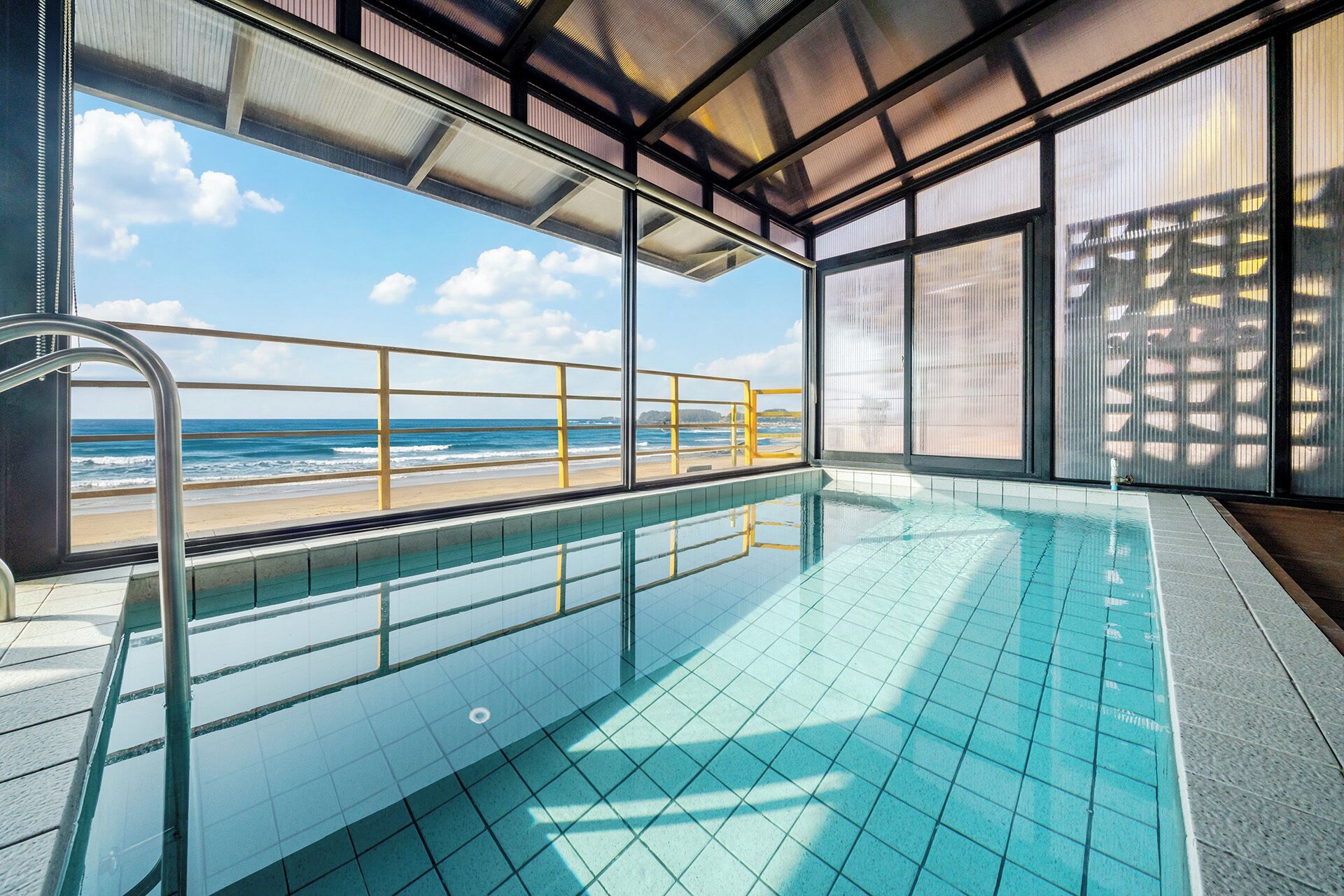 An indoor swimming pool with a view of the beach and ocean.