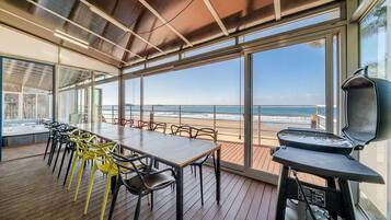 Terraza con mesa y sillas, con vista a la playa.