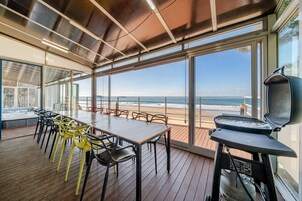Terraza con mesa y sillas, con vista a la playa.