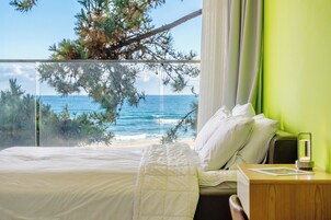 Una habitación de hotel con cama, mesita de noche, lámpara y vistas al océano.
