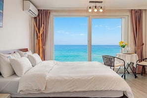 Une chambre d’hôtel avec un lit, un bureau et une vue sur l’océan.