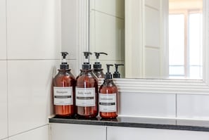Tres botellas de champú, gel de baño y acondicionador sobre una encimera.