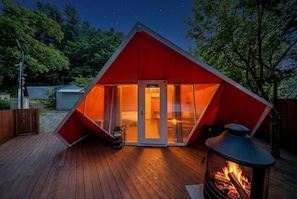 A triangular tent with a door labeled "Ciel" and a fire pit outside.