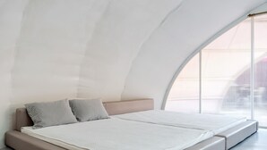 Un dormitorio moderno con techo curvo y una ventana grande.