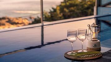 Una mesa con dos vasos y un farol en un balcón con vistas a un paisaje.