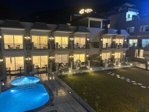 Een hotel met meerdere verdiepingen, balkons, een zwembad en een goed verlicht buitengebied.