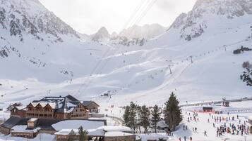 Ein schneebedecktes Bergresort mit Seilbahn, Holzhäusern und Skipiste.