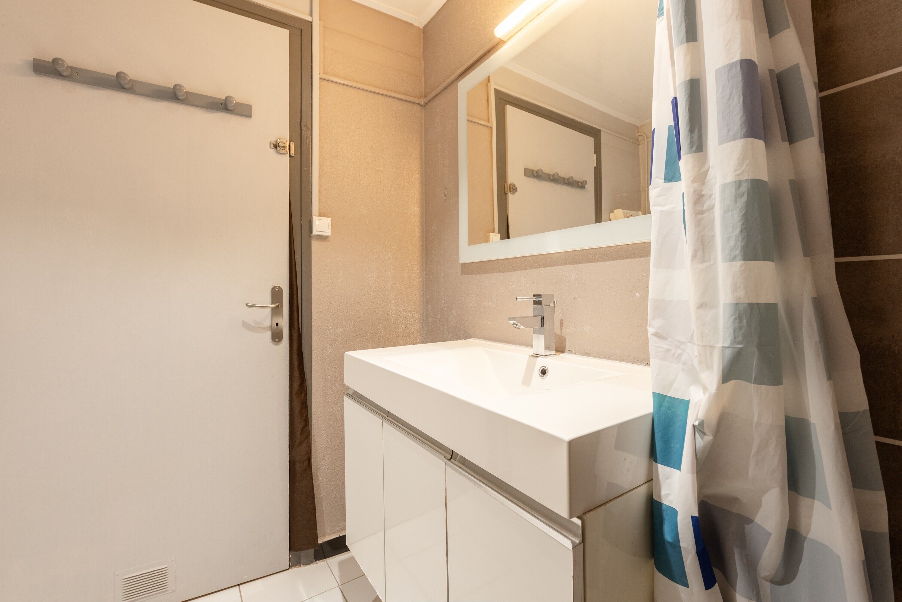A bathroom with a white sink, a mirror, and a shower curtain.