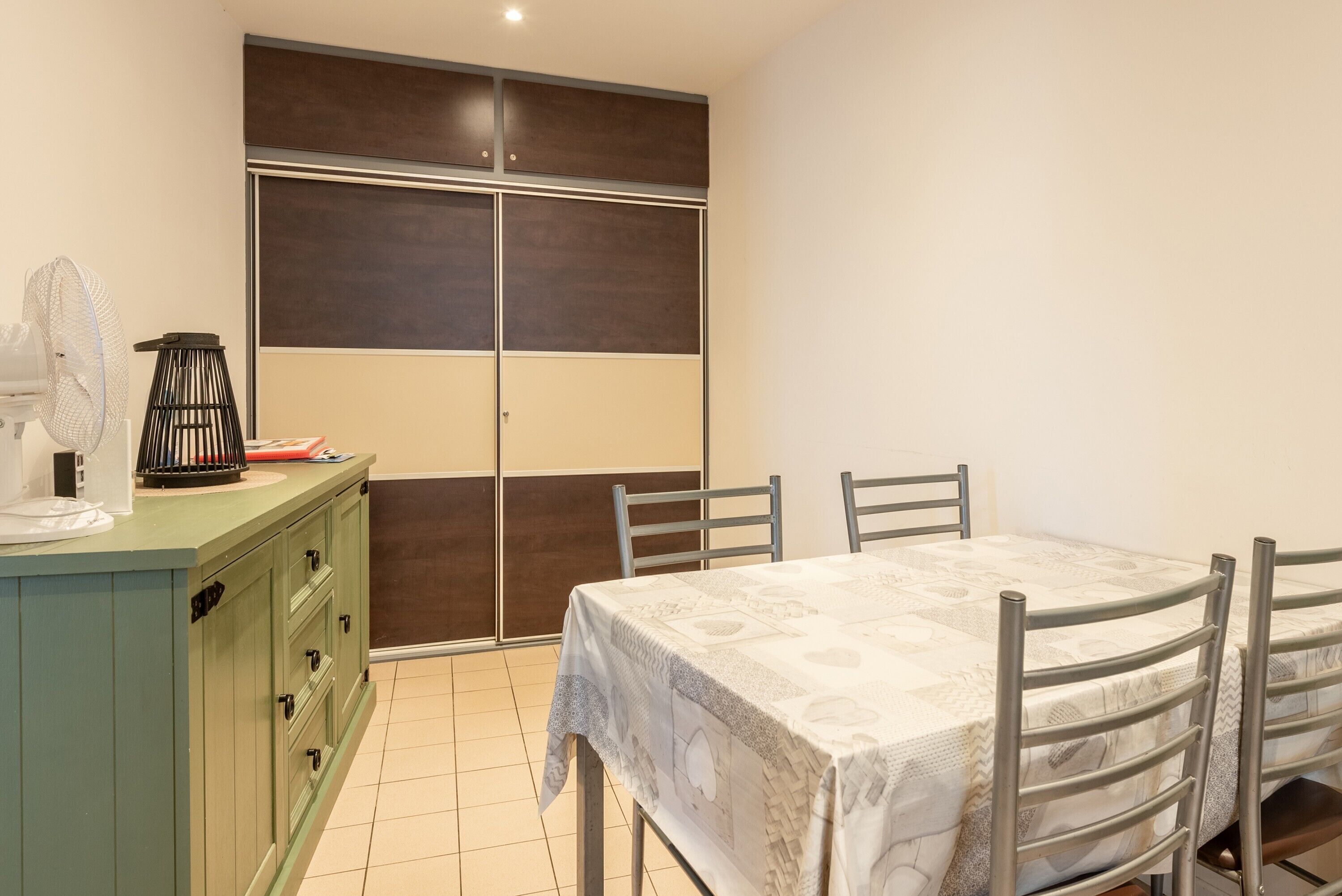 A room with a dining table, chairs, a green cabinet, and a sliding door.