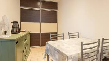 A room with a dining table, chairs, a green cabinet, and a sliding door.