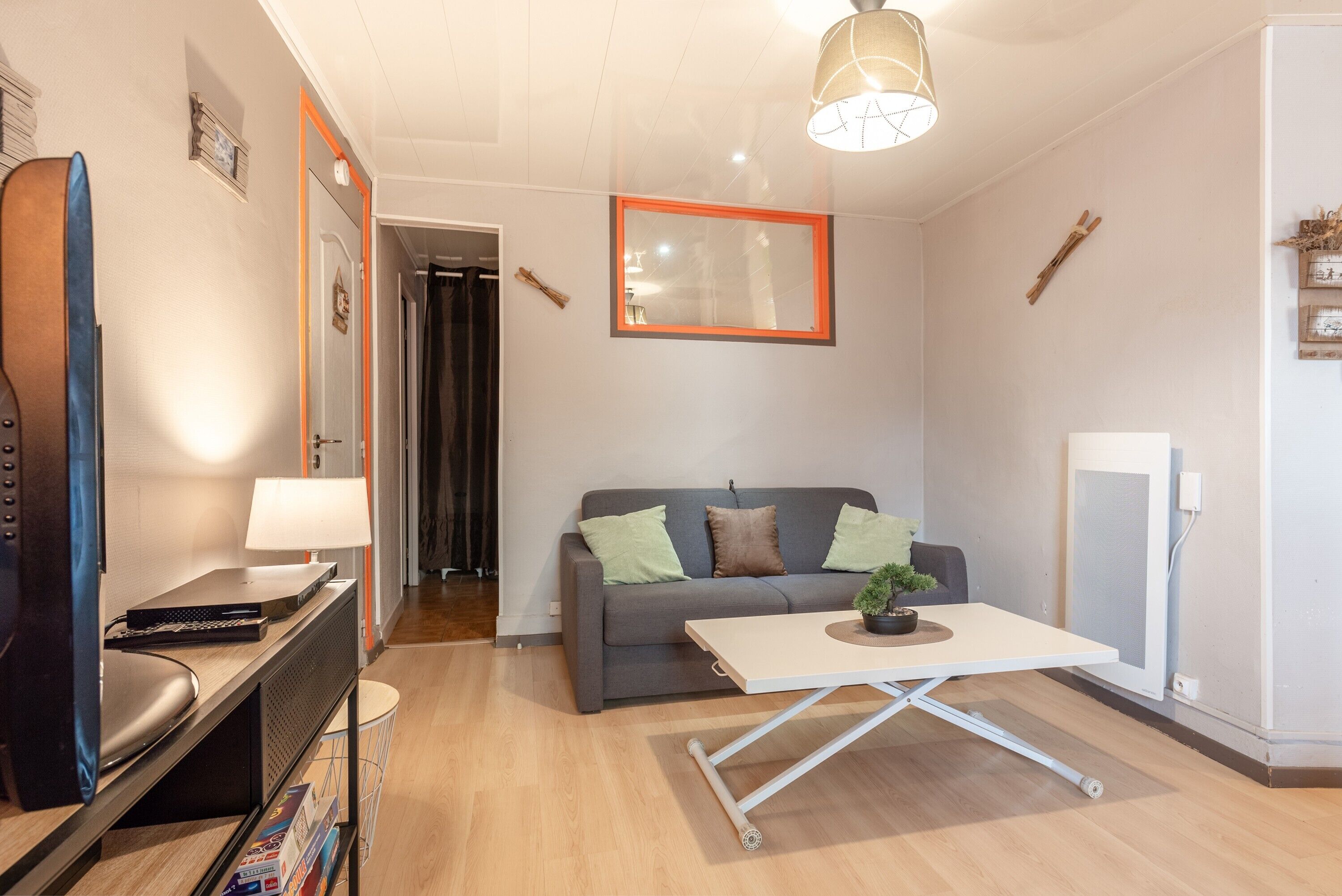 Una sala de estar con sofá, mesa de centro, televisor y lámpara.