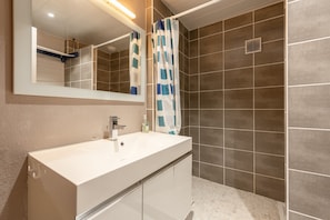 Un baño con lavamanos blanco, espejo y cortina de ducha.