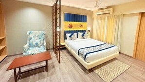 A bedroom with a bed, a chair, a small table, and a partition wall. - Enrise By Sayaji Vadodara (Vadodara)
