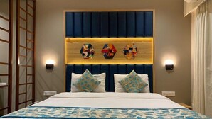 Una camera d'albergo con un letto grande, una testiera decorativa e due luci a parete.