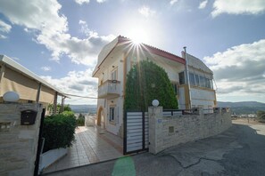 A two-story house with a red roof, a stone wall, and a gate. - Villa Thea (Moires)