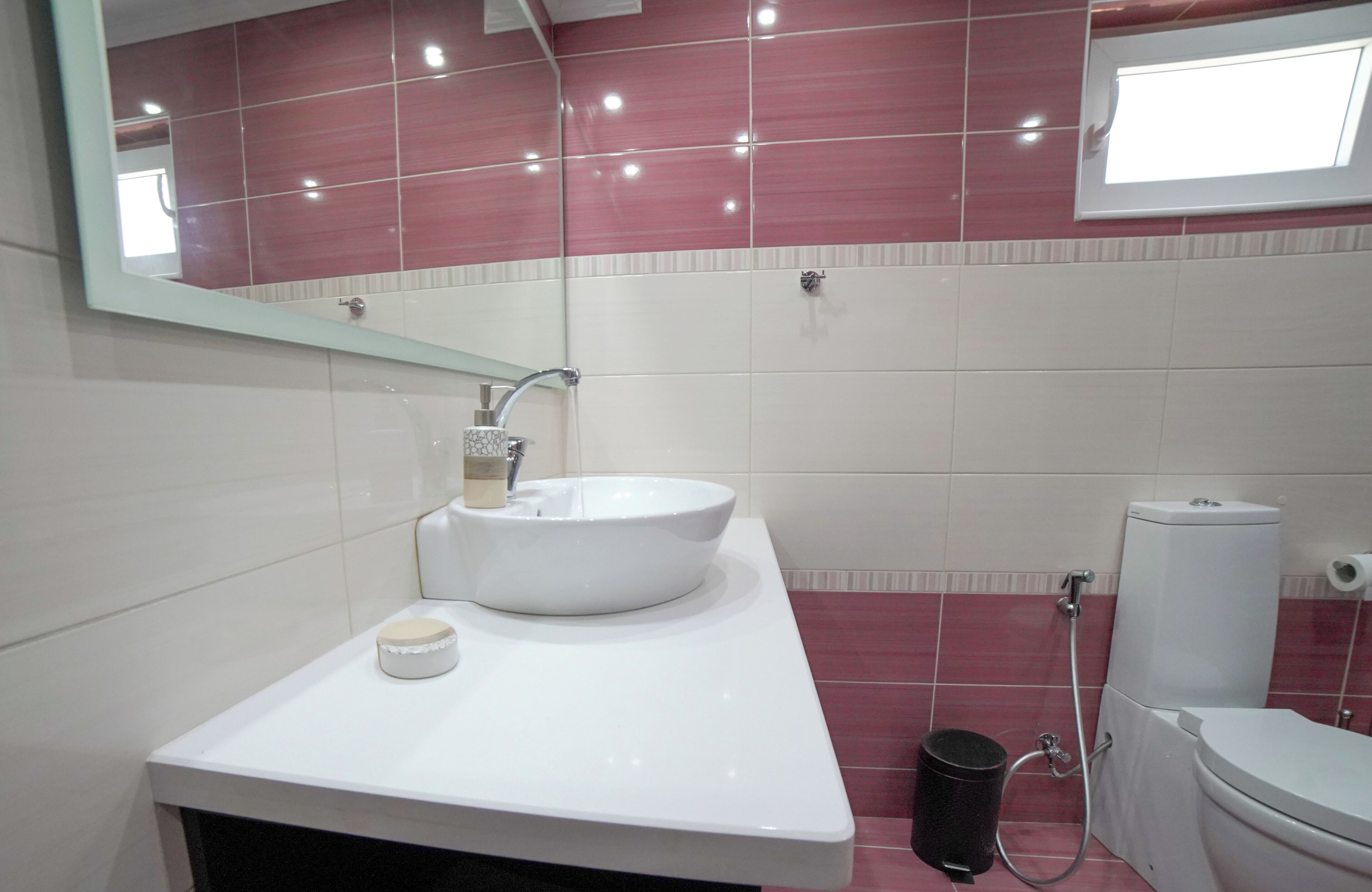 Une salle de bain avec un lavabo blanc, un miroir, des toilettes et une douche.
