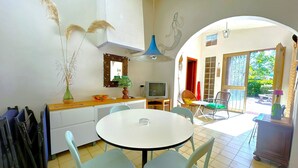 Zona pranzo con tavolo rotondo e sedie, televisione, lampada decorativa e un vaso con piume di pneumatide.