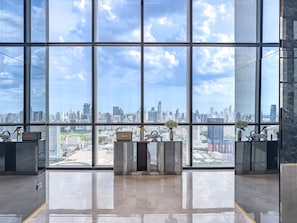 A spacious lobby with a city view through large windows, a reception desk, and modern decor. - Luxury Residence in Central of Bangkok Siam Paragon Central World (Bangkok)