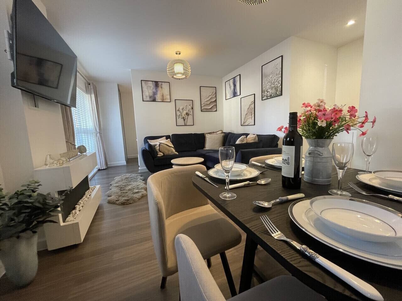 Ein moderner Essbereich mit Tisch für zwei Personen, einer Couch und einem an der Wand befestigten Fernseher.