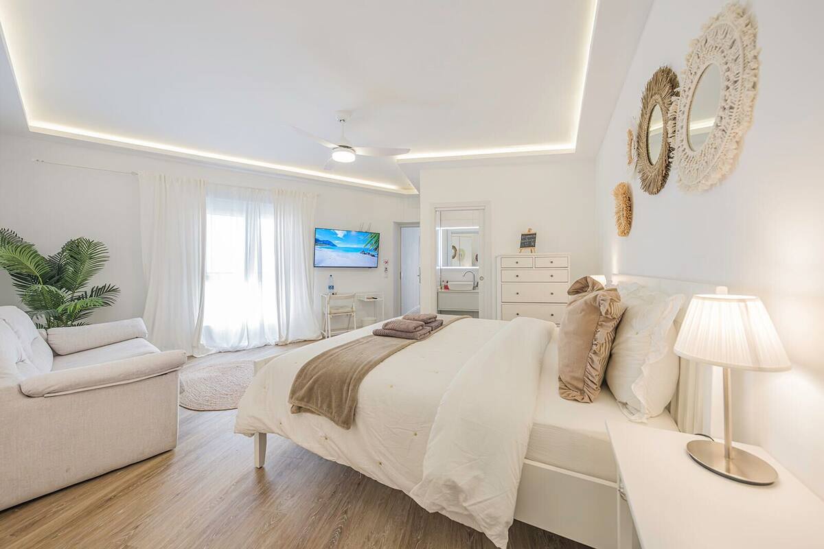A modern bedroom with a bed, bedside table, lamp, and a TV on the wall.