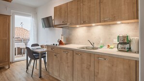 Una cocina moderna con armarios de madera, televisor integrado y comedor con sillas.