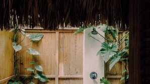 A wooden gate leading to a garden area with a concrete path, surrounded by various plants and a small sink area. - ¨El Refugio¨3 bedroom bungalow with pool & A/C near Macao beach (Punta Cana)