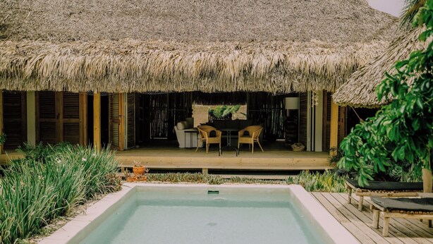 A thatched-roof outdoor area with a pool, wooden deck, and lounge chairs. - ¨El Refugio¨3 bedroom bungalow with pool & A/C near Macao beach (Punta Cana)