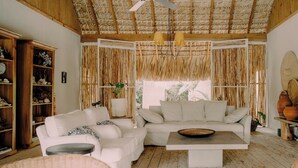 A spacious living room with a high ceiling, a large sofa set, a coffee table, and a bookshelf. - ¨El Refugio¨3 bedroom bungalow with pool & A/C near Macao beach (Punta Cana)