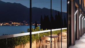 A balcony with a view of a lake and mountains at dusk. - WIND HOTEL (Malcesine)