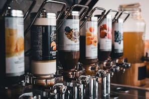 A coffee machine with multiple dispensers, each labeled with different coffee types. - WIND HOTEL (Malcesine)