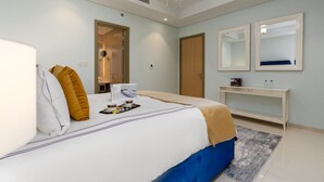 Ein modernes Hotelzimmer mit einem großen Bett, einem Nachttisch, einem Spiegel und einer Tür zu einem Badezimmer.