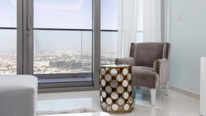Ein modernes Wohnzimmer mit Blick auf eine Stadtlandschaft durch große Fenster, ein grauer Sessel und ein dekorativer Beistelltisch.