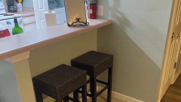 A kitchen with a bar stool seating area, a welcome sign, and a 'KITCHEN' sign on the wall. - Welcome to Steve & Tracie’s Gulf Retreat!  (Gautier)