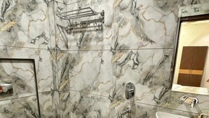 Une salle de bain avec un sol en marbre, un lavabo blanc, des toilettes et un espace douche.