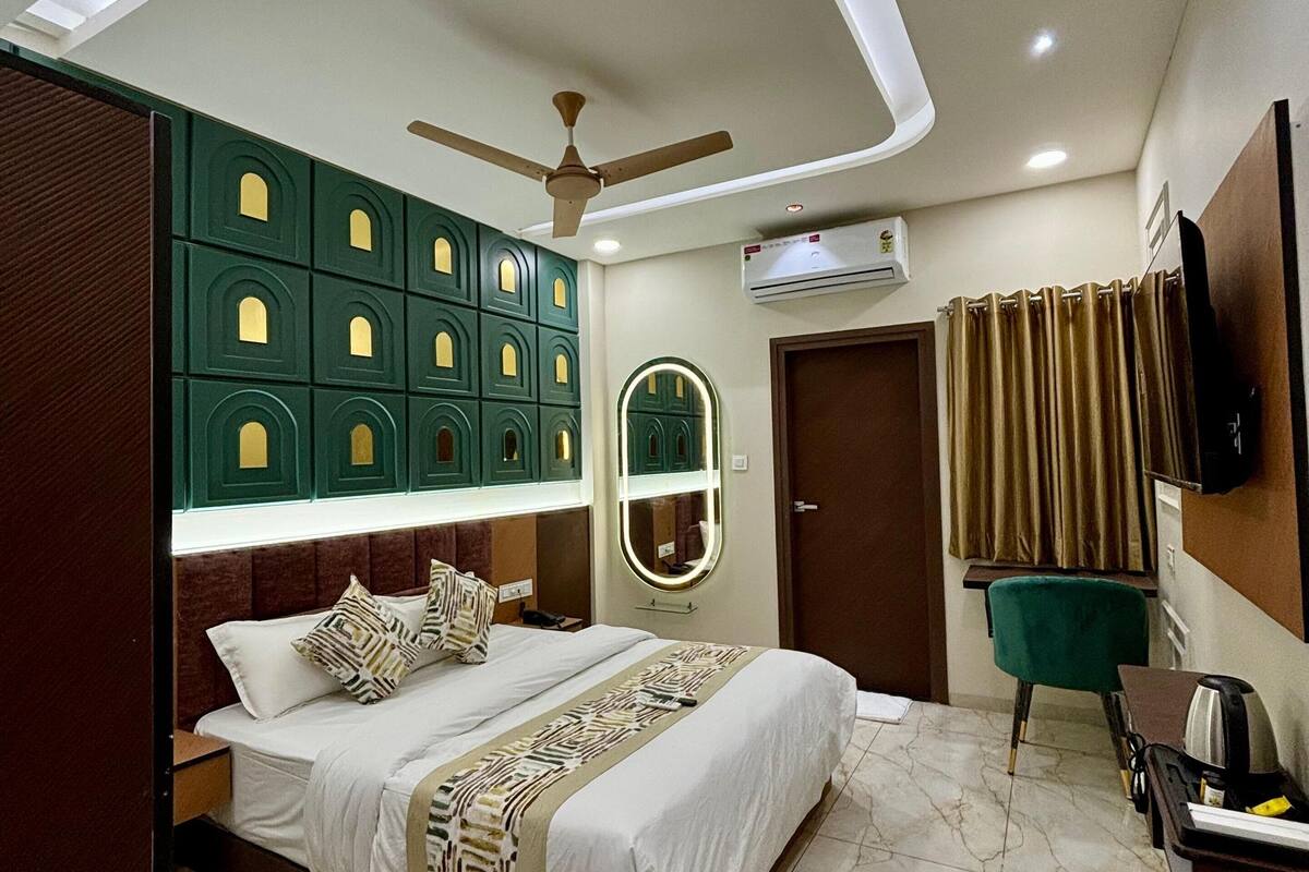 A modern bedroom with a bed, a ceiling fan, a built-in wardrobe, an air conditioning unit, and a television on the wall.