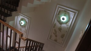 Un escalier avec des rampes en bois et un mur percé de deux fenêtres éclairées.