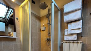 A modern bathroom with a glass-enclosed shower, a sink, a towel rack, and a radiator.
