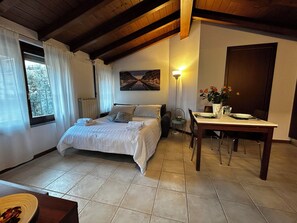 A bedroom with a bed, a dining table with chairs, a lamp, and a painting on the wall. - CasanovaSuite Milan (Milano)