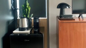 Une petite cuisine équipée, comprenant une machine à café, un petit haut-parleur et une plante en pot, le tout posé sur un plan de travail.