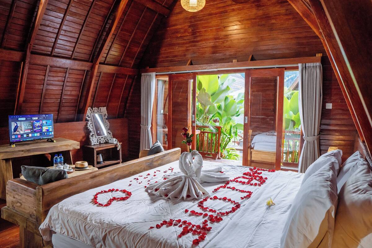 A wooden room with a bed, a desk, and a TV.