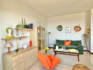 A living room with a green sofa, orange chair, wooden cabinet, and various decorative items. - D1MORA Oleandro apartment with terrace LAKE VIEW in central area in Tignale (Gardola)