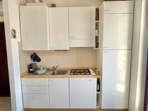 A compact kitchen with white cabinets, a sink, a stove, and a refrigerator. - D1MORA Oleandro apartment with terrace LAKE VIEW in central area in Tignale (Gardola)