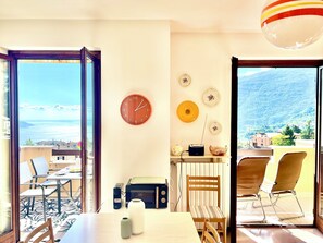 A room with a view of the sea, a clock, and a table with chairs. - D1MORA Oleandro apartment with terrace LAKE VIEW in central area in Tignale (Gardola)