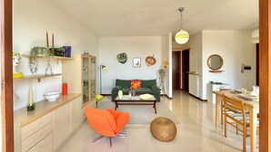 Ein großzügiger Wohnbereich mit Sofa, einem Esstisch mit Stühlen, einer Küchenzeile und einem Flur, der in einen weiteren Raum führt.