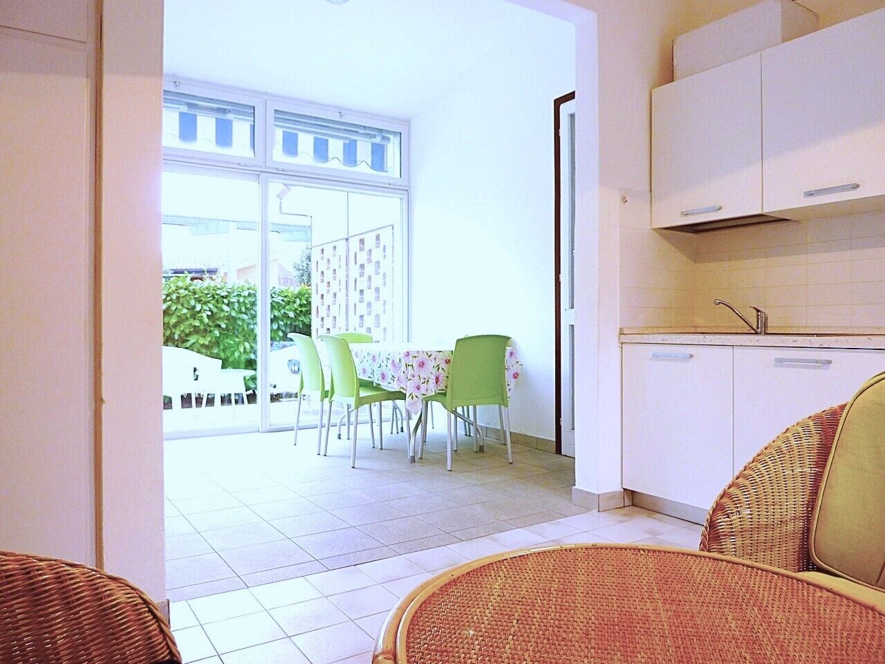 A room with a dining area, a kitchen, and a view of the outside.